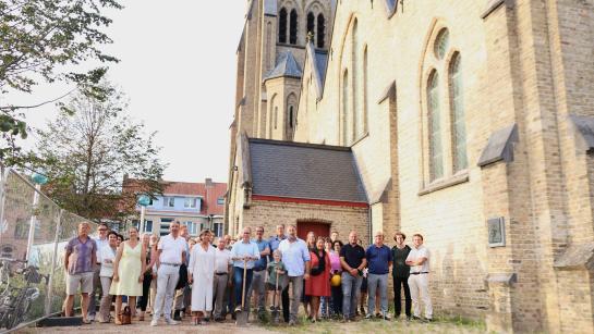 Inwoners en bestuur staan symbolisch samen met de spade voor de kerk