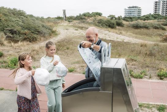 Opa met kleinkinderen dropt afval in de container